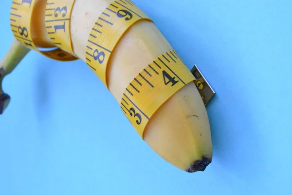 Different types of fruit, such as apples, cherries and bananas lie on a single-footed base and are wrapped in a measuring tape - concept for healthy weight loss that makes fun