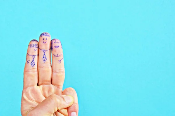 On the index and middle finger of a middle-aged man, two persons' faces with glasses and a tie were drawn with a ballpoint pen - concept with space for text or other elements