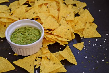 Koyu mermer bir yüzeyde soğan ve birçok baharat ile ev yapımı guacamole bir kase yanında tuz ile nachos bir yığın var - metin için alan ile lezzetli atıştırmalık
