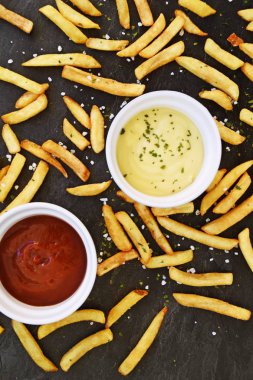  taze patates kızartması ve tuz taneleri ve baharatlar yalan koyu mermer arka plan, ketçap dolu bir kapta kızartılmış altın sarısı taze patates kızartması