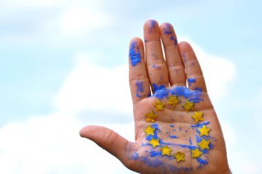 Bir kişi bulutlu bir gökyüzü önünde elini tutuyor , el sarı kağıt yıldız ile Avrupa Birliği renkleri ile boyanmıştır - kavram ab ve oy özgürlüğü kutlamak için