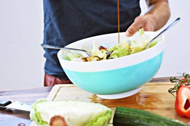 Taze yapılmış bir salata üzerine sos dökün - ahşap bir masada domates, salatalık ve biber ile taze salata bir kase yakın 