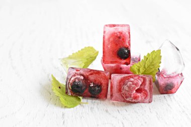 Yaz aylarında serinletici soğutma olarak, hafif ahşap bir yüzey üzerinde yalan içinde donan çeşitli çilek ile buz küpleri - Buz küpleri lezzetli ve organik çilek
