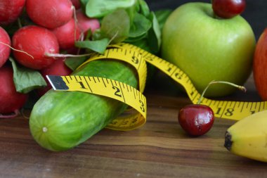 Taze gevrek sebzeler bir einfabrigen tabanı üzerinde yatan bir ölçüm bandı ile sarılmış - kilo vermek için sağlıklı beslenme için kavram