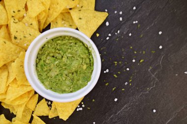 Koyu mermer bir yüzeyde soğan ve birçok baharat ile ev yapımı guacamole bir kase yanında tuz ile nachos bir yığın var - metin için alan ile lezzetli atıştırmalık