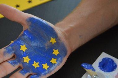 Bir kişi bulutlu bir gökyüzü önünde elini tutuyor , el sarı kağıt yıldız ile Avrupa Birliği renkleri ile boyanmıştır - kavram ab ve oy özgürlüğü kutlamak için