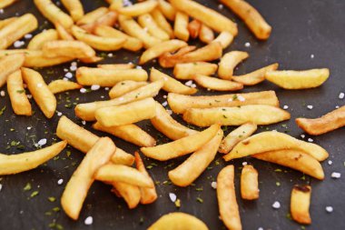 Deniz tuzu taneleri ve patates kızartması baharat ile koyu mermer yüzeyüzerinde taze patates gevrek kavrulmuş cips - Lezzetli fast food kızarmış altın sarısı