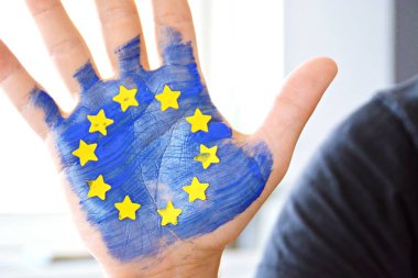 Bir kişi bulutlu bir gökyüzü önünde elini tutuyor , el sarı kağıt yıldız ile Avrupa Birliği renkleri ile boyanmıştır - kavram ab ve oy özgürlüğü kutlamak için
