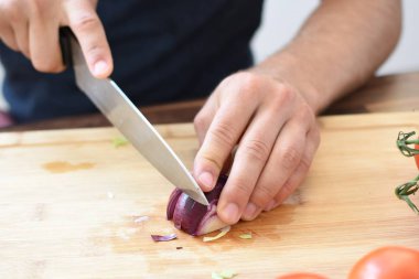 Bir kişi taze gevrek sağlıklı salata için ahşap bir tahta üzerinde kırmızı soğan keser - kişinin elinde yakın çekim - taze organik sebze ile sağlıklı beslenme için kavram