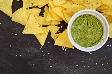 Koyu mermer bir yüzeyde soğan ve birçok baharat ile ev yapımı guacamole bir kase yanında tuz ile nachos bir yığın var - metin için alan ile lezzetli atıştırmalık