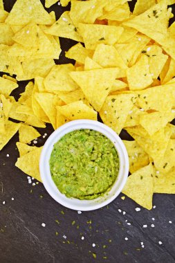 Koyu mermer bir yüzeyde soğan ve birçok baharat ile ev yapımı guacamole bir kase yanında tuz ile nachos bir yığın var - metin için alan ile lezzetli atıştırmalık