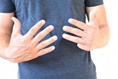 Genç bir adam boynuz parmakları gösterir - farklı ülkelerde farklı anlamları olan bir jest, adamın ellerine odaklanarak 