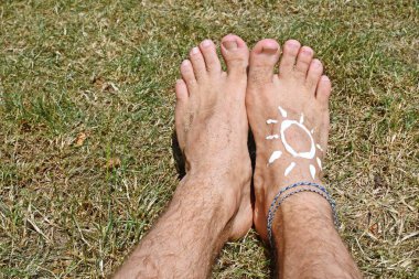 Bir bileklik ile bir erkek ayak ile sıcak plaj günlerinde güneşten korunmak için kavram 