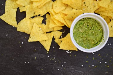 Koyu mermer bir yüzeyde soğan ve birçok baharat ile ev yapımı guacamole bir kase yanında tuz ile nachos bir yığın var - metin için alan ile lezzetli atıştırmalık