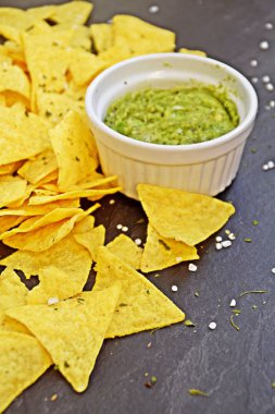 Koyu mermer bir yüzeyde soğan ve birçok baharat ile ev yapımı guacamole bir kase yanında tuz ile nachos bir yığın var - metin için alan ile lezzetli atıştırmalık
