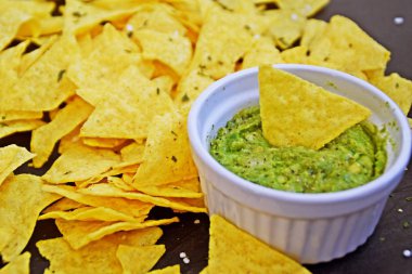 Koyu mermer bir yüzeyde soğan ve birçok baharat ile ev yapımı guacamole bir kase yanında tuz ile nachos bir yığın var - metin için alan ile lezzetli atıştırmalık