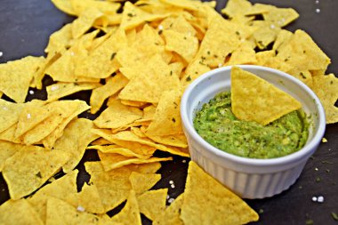 Koyu mermer bir yüzeyde soğan ve birçok baharat ile ev yapımı guacamole bir kase yanında tuz ile nachos bir yığın var - metin için alan ile lezzetli atıştırmalık