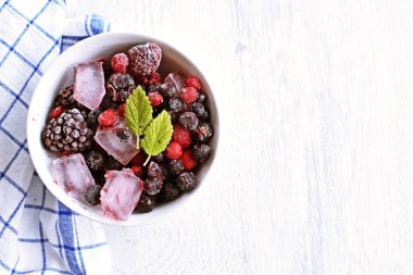 Yaz aylarında serinletici soğutma olarak, hafif ahşap bir yüzey üzerinde yalan içinde donan çeşitli çilek ile buz küpleri - Buz küpleri lezzetli ve organik çilek