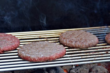 Bir ızgara üzerinde bir ev yapımı burger için yarım kızarmış kıyılmış köfte vardır - kömür ve taze köfte ile yaz aylarında Barbekü için arka plan -