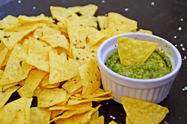 Koyu mermer bir yüzeyde soğan ve birçok baharat ile ev yapımı guacamole bir kase yanında tuz ile nachos bir yığın var - metin için alan ile lezzetli atıştırmalık