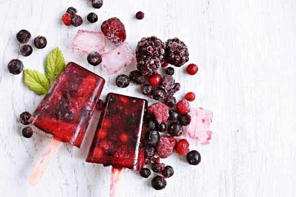 Homemade popsicles of wild berries with berries and mint leaves - refreshing healthy organic ice