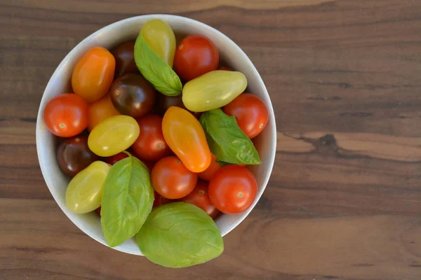 Different types of tomatoes in different colors and basil - concept with fresh and healthy different tomatoes, with space for text for other elements
