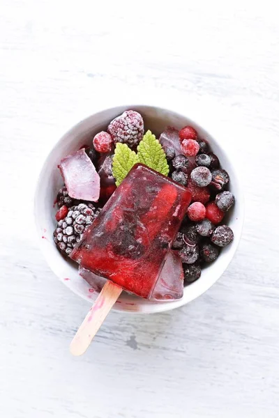 Homemade popsicles of wild berries with berries and mint leaves - refreshing healthy organic ice