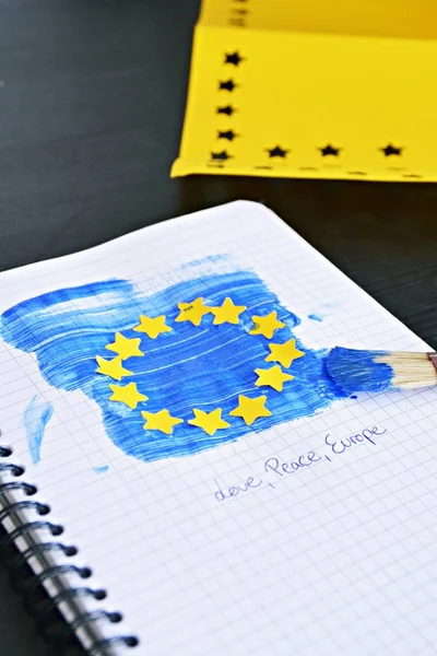 With a brush and blue paint, as well as punched out yellow paper stars, the flag of the EU was drawn on a block sheet - Concept for Europe and the unity in the EU to match the European elections