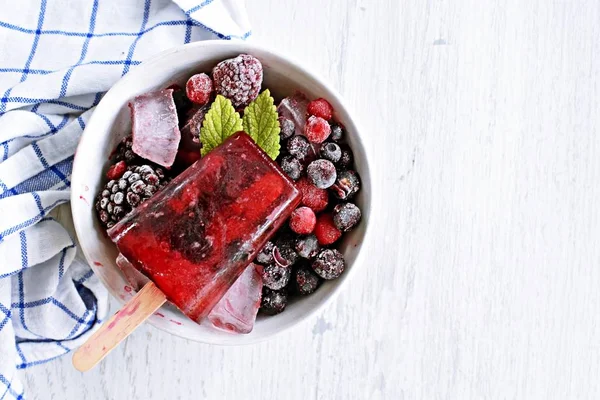 Homemade popsicles of wild berries with berries and mint leaves - refreshing healthy organic ice