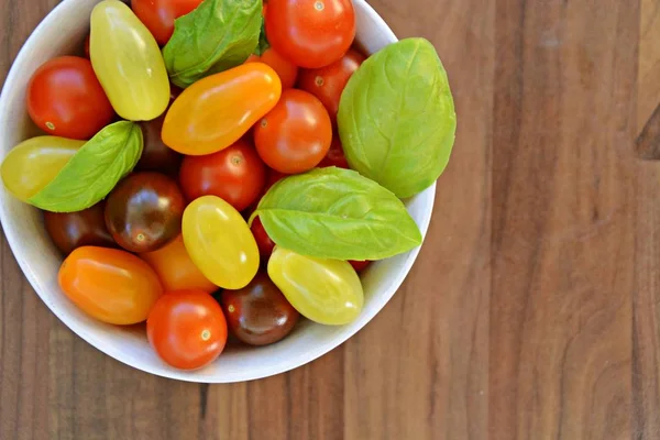 Different types of tomatoes in different colors and basil - concept with fresh and healthy different tomatoes, with space for text for other elements