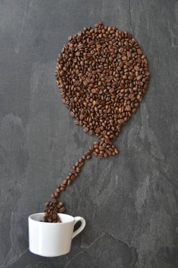Bir balon bir kahve bardağı üzerinde bir balon şeklinde kahve çekirdekleri ile beyaz bir kahve fincan-konsept dışarı geliyor