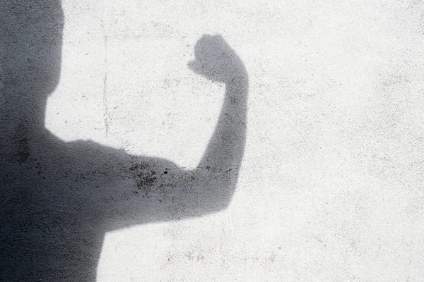 shadow of man gesturing fight on white wall