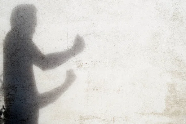 shadow of man gesturing fight on white wall