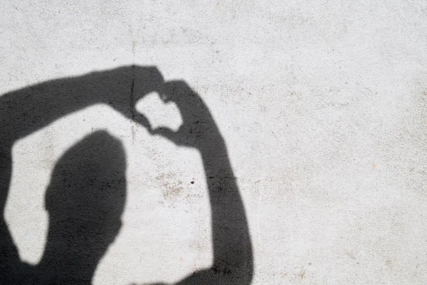 shadow of man gesturing heart on white wall
