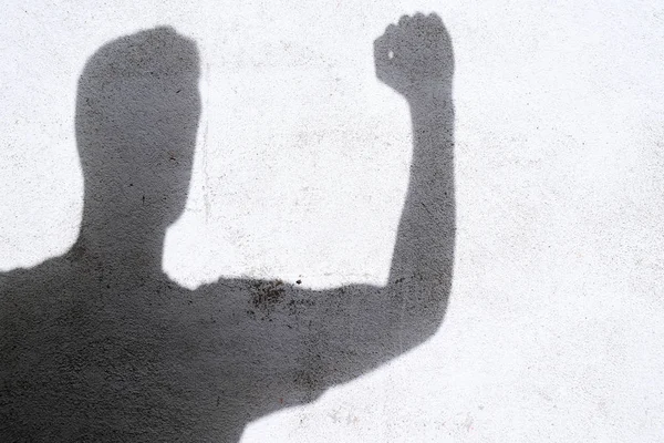 shadow of man gesturing fight on white wall