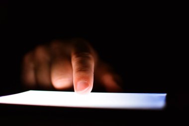 Karanlıkta aydınlatma ekranı olan akıllı telefon kullanan kişinin kısmi görüntüsü