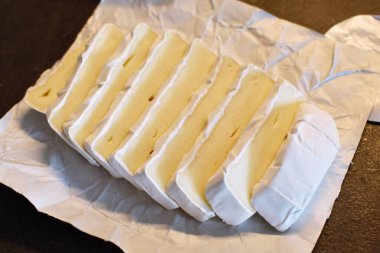 Dilimler halinde dilimler halinde dilimler halinde dilimlenmiş camembert peyniri. Lezzetli, taze camembert, koyu ahşap bir yüzey üzerinde.