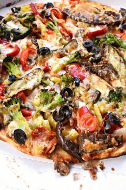 Pizza servisinden üstü mantar, zeytin, brokoli, soğan ve biber gibi sebzelerle kaplı pizza. Pizza kutusundaki lezzetli vejetaryen pizza, taze ve yemeye hazır.
