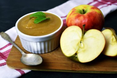 Bir kase ev yapımı elma püresi tarçınlı ve şekerli. Masada elma parçaları var.
