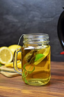 Tahta masada taze nane yapraklı bir bardak limon çayı.