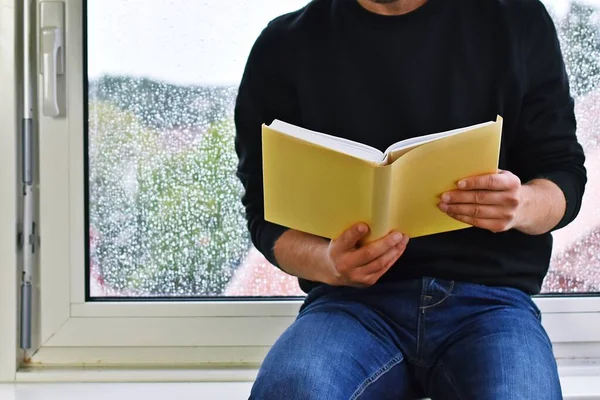 Adam Pencere Pervazında Oturuyor Pencere Kenarındaki Yağmur Damlalarında Kitap Okuyor — Stok fotoğraf