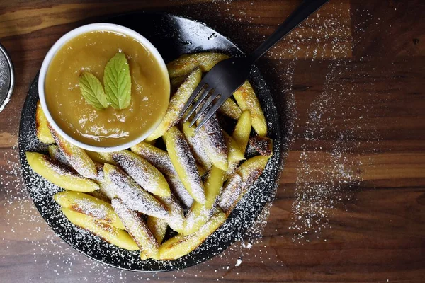 Delicious, fried Schupfnudeln from Germany covered with icing sugar next to a bowl of apple sauce. Delicious dessert as a sweet lunch in Germany