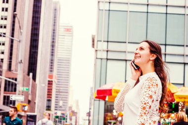 Genç Doğu Avrupa New York'ta seyahat beyaz, giyen kadın dantel kesip uzun kollu gömlek middletown Manhattan, modern binalar ile sokakta duran, cep telefonuyla konuşurken gülümseyen