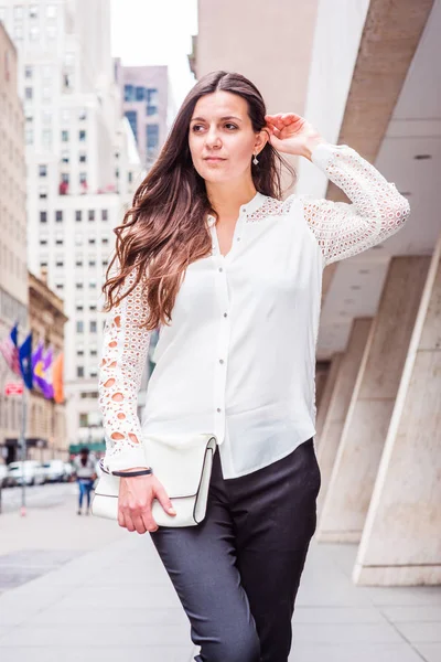 東ヨーロッパで若い女性長い黒い髪 ニューヨークの旅レースをカット長袖シャツ 黒パンツ 持株革小物財布 マンハッタンの通りの上を歩く — ストック写真