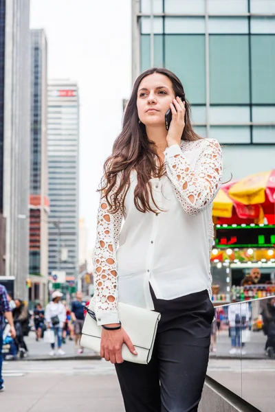 若い東ヨーロッパ実業家旅行 ニューヨークで仕事 白を着てレース カット長袖シャツ 黒パンツ ハンドバッグ マンハッタンの通りの上に立って 携帯電話で話しているを保持 — ストック写真