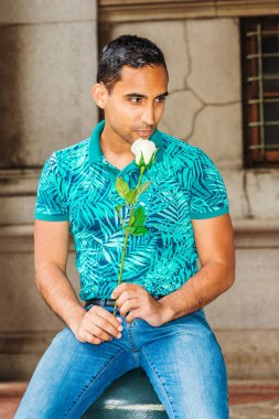 Mavi jeans, seyir, yalnız, vintage New York'ta sokak üzerinde oturan beyaz gül tutan genç Latin Amerikalı adam, seni özlüyorum, seni, yeşil giymiş desenli Polo Gömlek düşünüyorum düşünüyorum