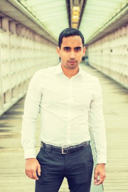 Genç yakışıklı İspanyol Amerikan beyaz gömlek, siyah pantolon giyen adam New York'ta portresi cam duvarın içinde bina, sana bakarken office ile geçit üzerinde duran