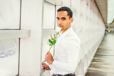 Genç Latin Amerikalı adam, seni özledim, seni düşünüp beyaz holding beyaz gömlek giymiş, geçit cam duvarın içinde burun ile kokulu çiçek New York'ta bina ofis ile üzerinde ayakta gül.