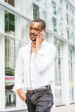 New York'ta seyahat sakallı genç Afro-Amerikan modern ofis Manhattan Caddesi üzerinde binası tarafından geçen cep telefonuyla konuşurken yürüyüş beyaz gömlek, siyah pantolon giyen adam gülümseyen.