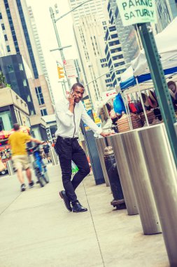 Afrikalı-Amerikalı New York'ta seyahat, beyaz gömlek, siyah pantolon, deri ayakkabılar giyen, street tarafından ayakta, telefonla arama adam. Yaz sokak adil ve adam sokakta ortasına bit pazarı